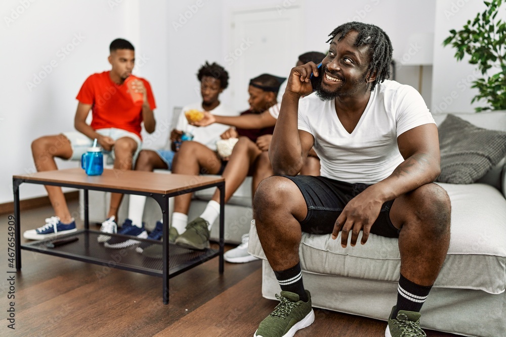 Group of african american people sitting on the sofa at home. Man smiling happy talking on the smartphone. Group of african american people sitting on the sofa at home. Man smiling happy talking on the smartphone.