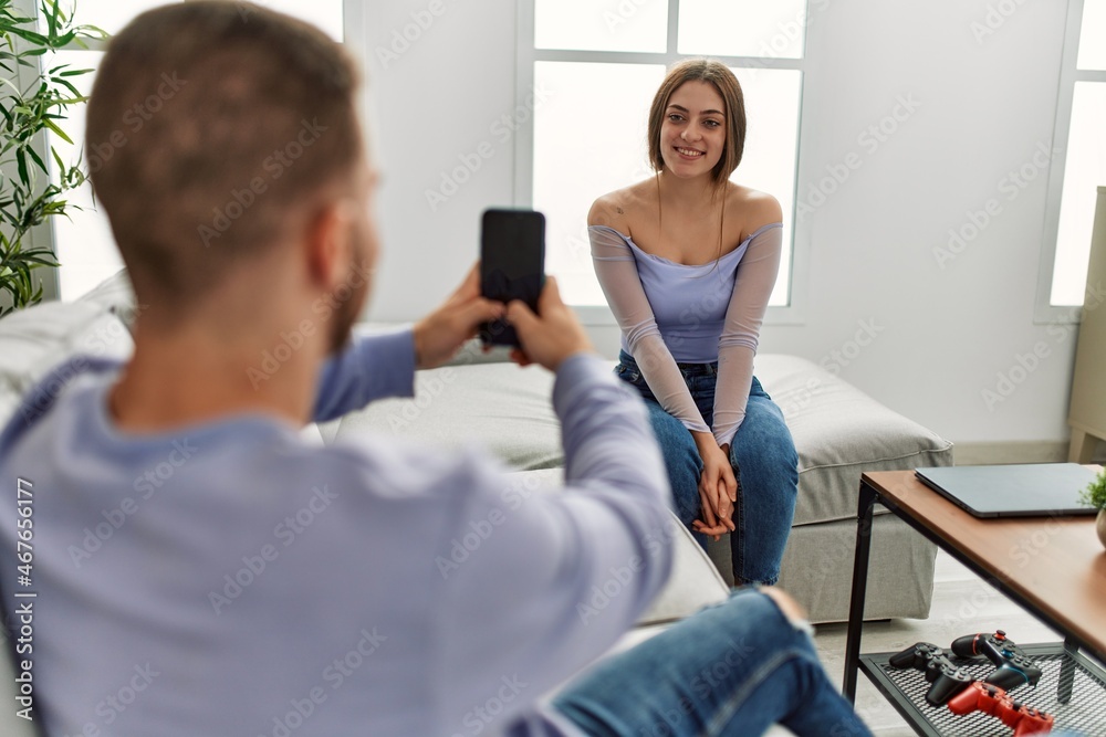 Young man making picture of his girlfriend using smartphone at home. Young man making picture of his girlfriend using smartphone at home.
