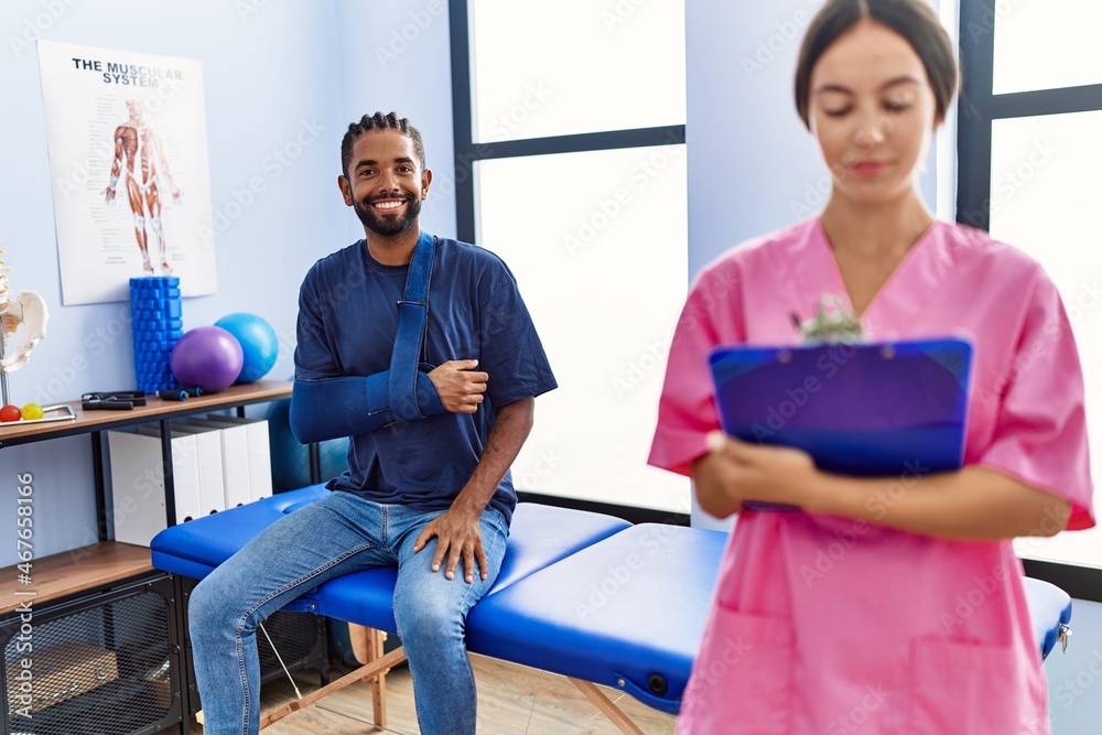 Man and woman wearing physiotherapist uniform having rehab session at physiotherpy clinic