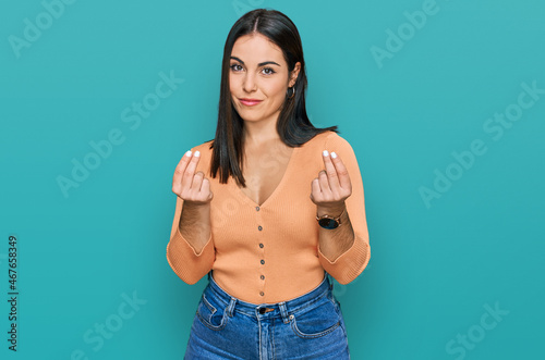 Young hispanic woman wearing casual clothes doing money gesture with hands, asking for salary payment, millionaire business