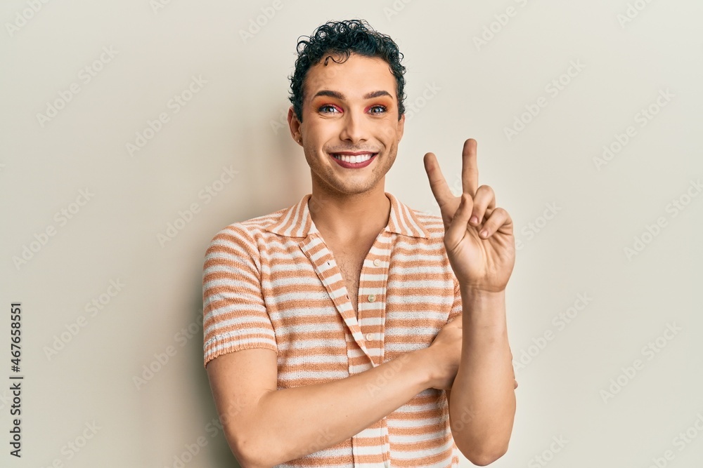 Handsome man wearing make up wearing casual t shirt smiling with happy face winking at the camera doing victory sign. number two. Handsome man wearing make up wearing casual t shirt smiling with happy face winking at the camera doing victory sign. number two.