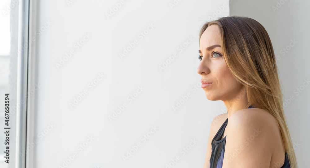 Sad beautiful woman looking through a window, copy space. Sad beautiful woman looking through a window, copy space.