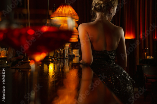 Valokuva Back of elegant lady in black shiny evening dress staing near bar counter
