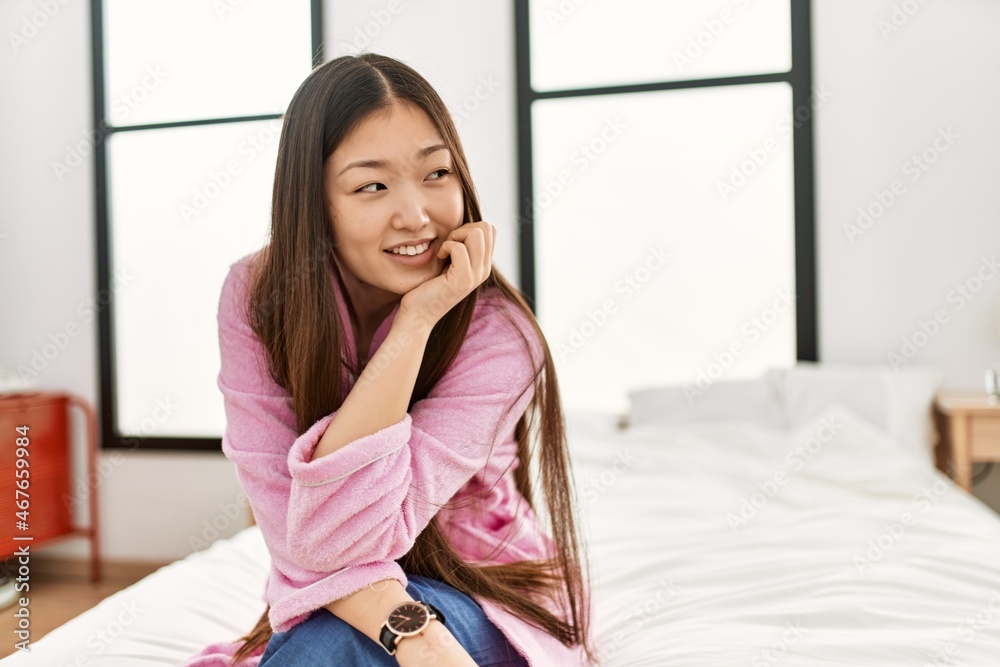 Young chinese girl smiling happy sitting on the bed at bedroom. Young chinese girl smiling happy sitting on the bed at bedroom.