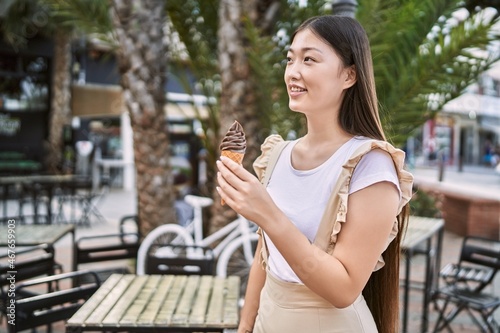 Young chinese girl smiling happy eating ice cream at the city.