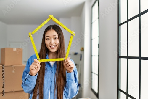 Young chinese girl smiling happy holding house project standing at new home