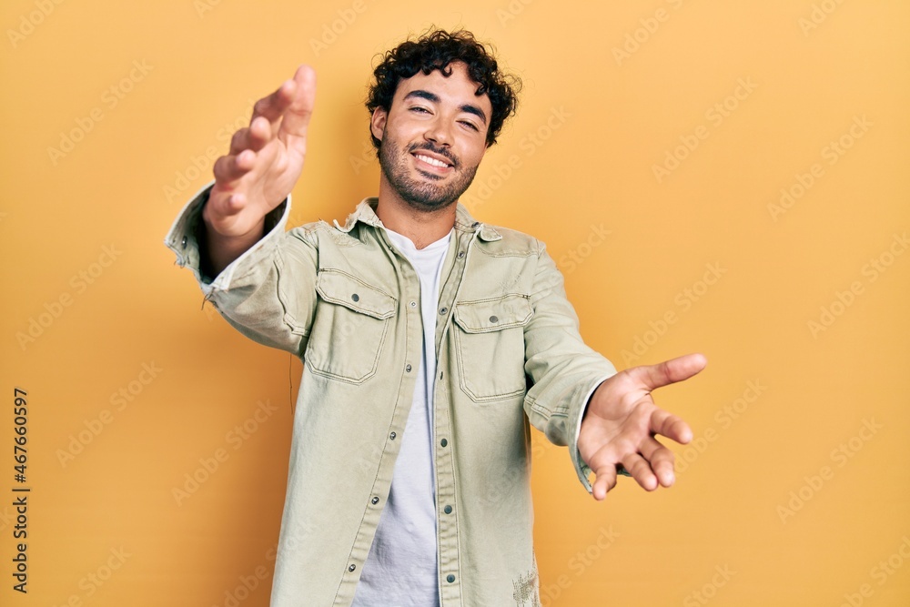 Young hispanic man wearing casual clothes looking at the camera smiling with open arms for hug. cheerful expression embracing happiness. Young hispanic man wearing casual clothes looking at the camera smiling with open arms for hug. cheerful expression embracing happiness.