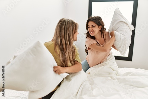 Young couple smiling happy fighting with pillows on the bed at home.