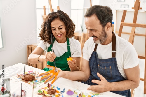 Two middle age student smiling happy painting hands at art studio.