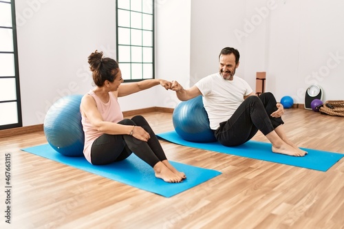Mature hispanic couple doing excersice and stretching at yoga room. Two adult people doing pilates and flexibility workout