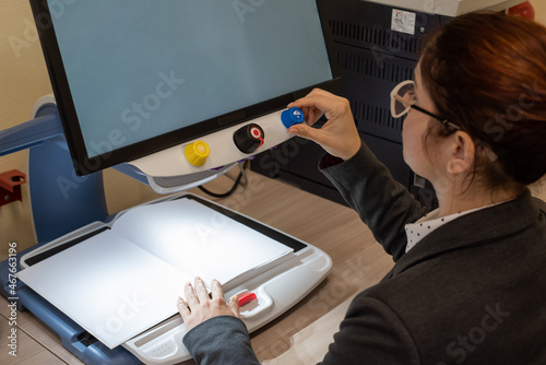 A visually impaired woman uses special reading equipment photo