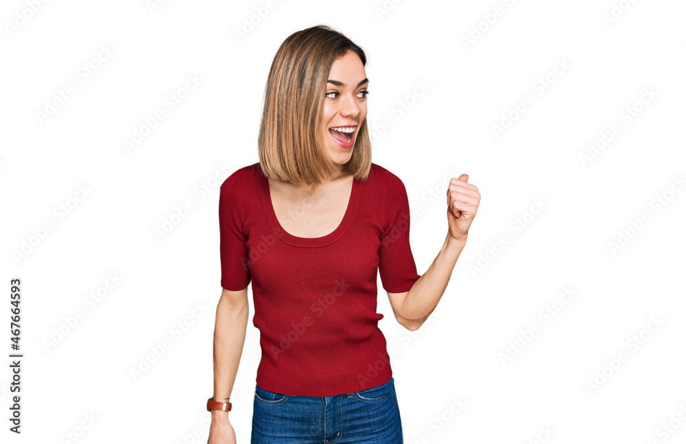 Young blonde girl wearing casual clothes smiling with happy face looking and pointing to the side with thumb up. Young blonde girl wearing casual clothes smiling with happy face looking and pointing to the side with thumb up.