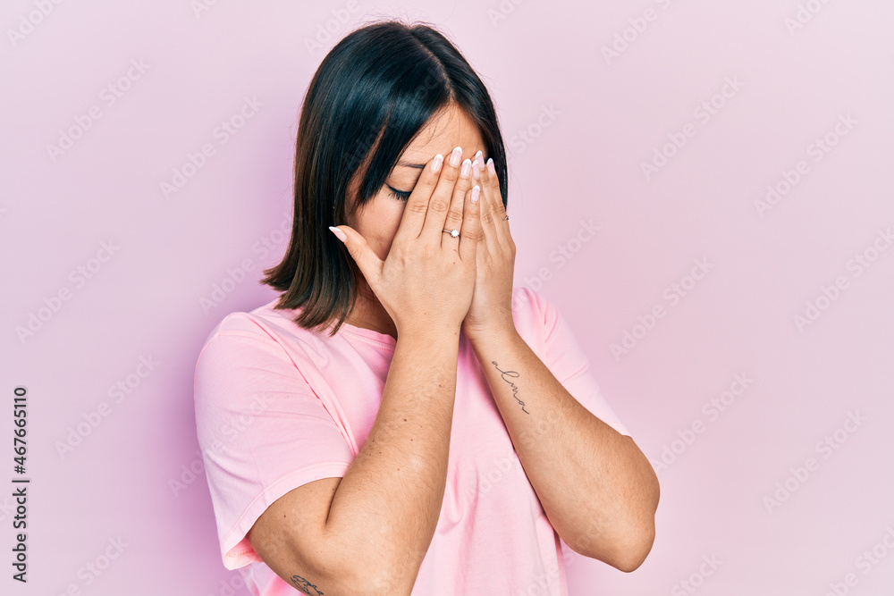 Young hispanic woman wearing casual pink t shirt with sad expression covering face with hands while crying. depression concept. Young hispanic woman wearing casual pink t shirt with sad expression covering face with hands while crying. depression concept.