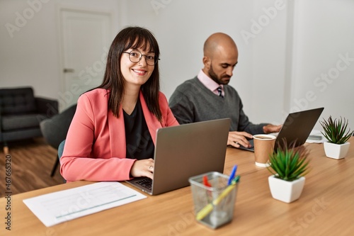 Two hispanic business workers smiling happy working at the office.