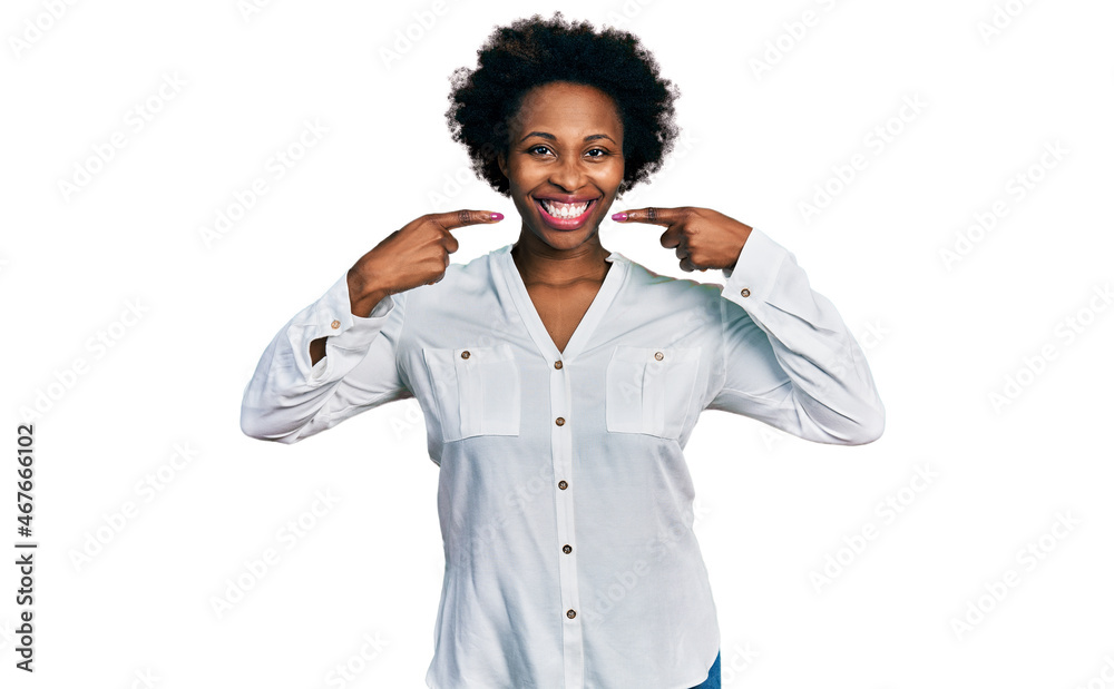African american woman with afro hair wearing casual white t shirt smiling cheerful showing and pointing with fingers teeth and mouth. dental health concept. African american woman with afro hair wearing casual white t shirt smiling cheerful showing and pointing with fingers teeth and mouth. dental health concept.