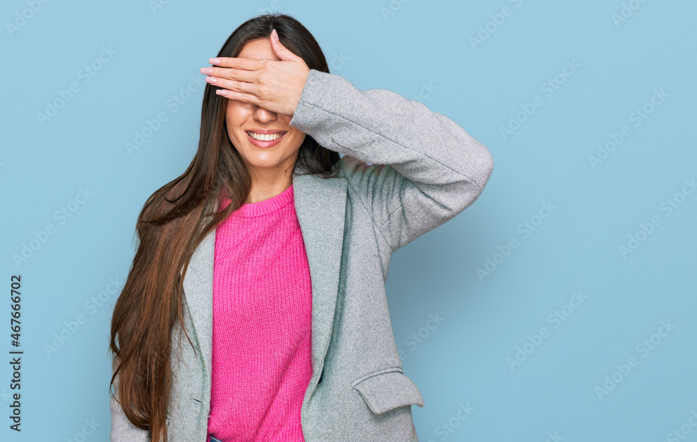 Young hispanic girl wearing business clothes smiling and laughing with hand on face covering eyes for surprise. blind concept.