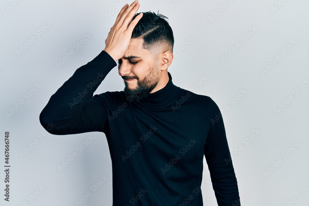 Handsome man with beard wearing turtleneck sweater surprised with hand on head for mistake, remember error. forgot, bad memory concept. Handsome man with beard wearing turtleneck sweater surprised with hand on head for mistake, remember error. forgot, bad memory concept.