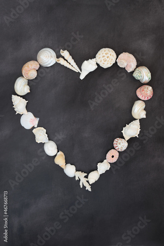 Abstract heart shape wreath with sea shells on mottled dark grey background. Valentine romantic minimal concept symbol. Flat lay, top view copy space. © marilyn barbone