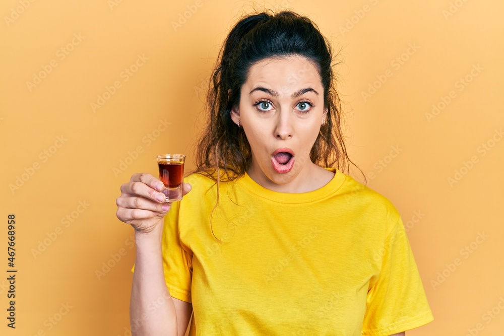 Young hispanic woman drinking whiskey shot scared and amazed with open mouth for surprise, disbelief face Young hispanic woman drinking whiskey shot scared and amazed with open mouth for surprise, disbelief face