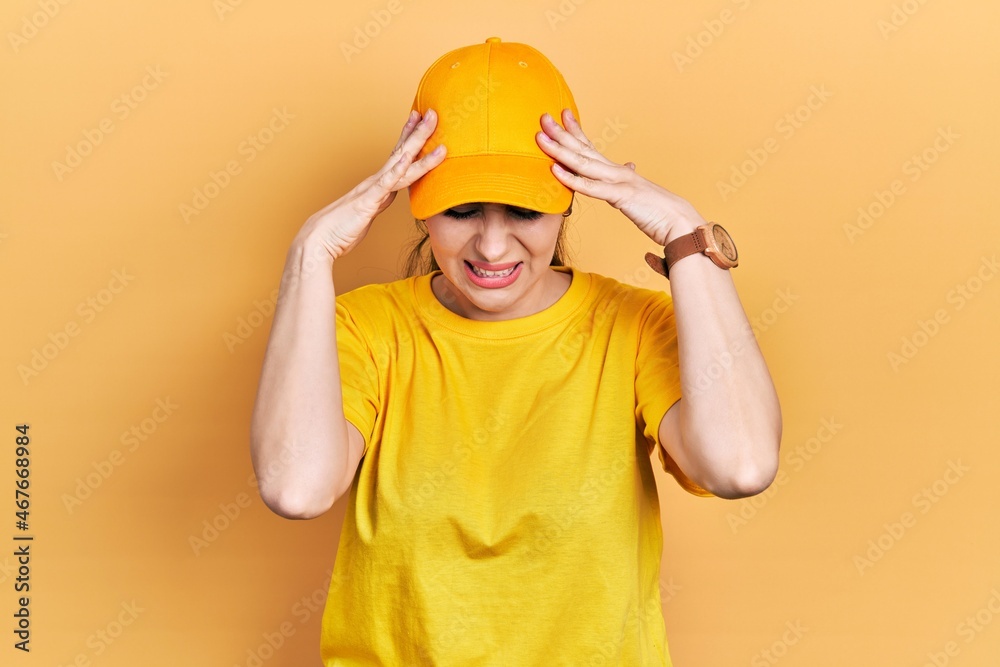 Young hispanic woman wearing delivery uniform and cap with hand on head for pain in head because stress. suffering migraine.