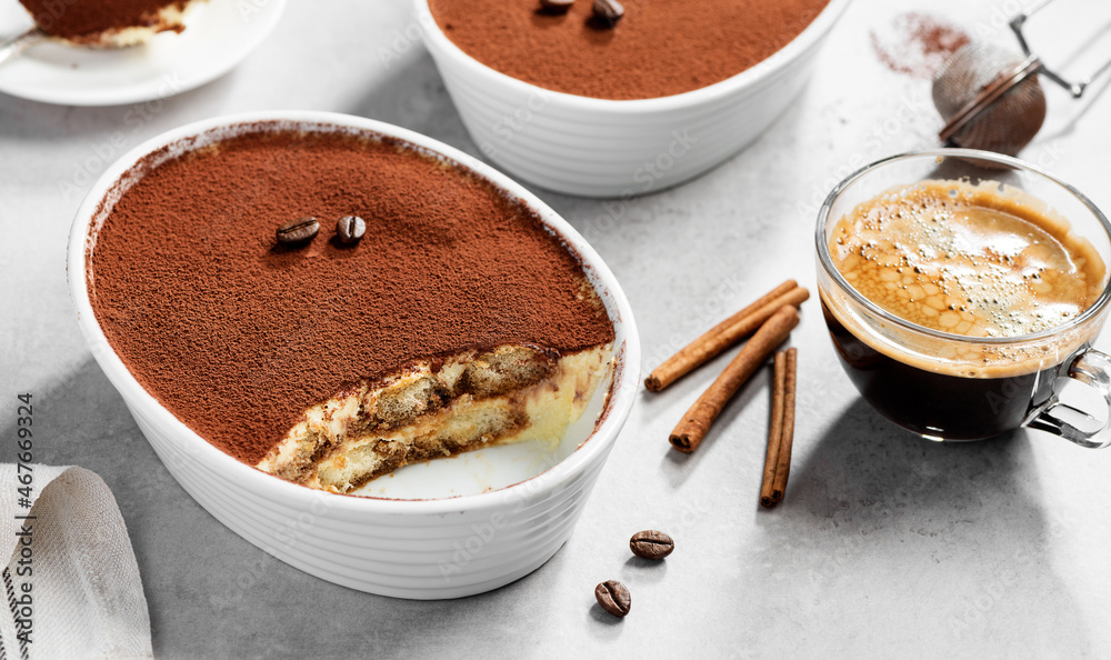 Classic Italian Dessert Tiramisu topped with cocoa in a ceramic dish. Light gray background. Classic Italian Dessert Tiramisu topped with cocoa in a ceramic dish. Light gray background.
