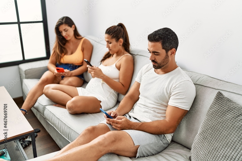 Three hispanic friends with serious expression using smartphone sitting on the sofa at home. Three hispanic friends with serious expression using smartphone sitting on the sofa at home.