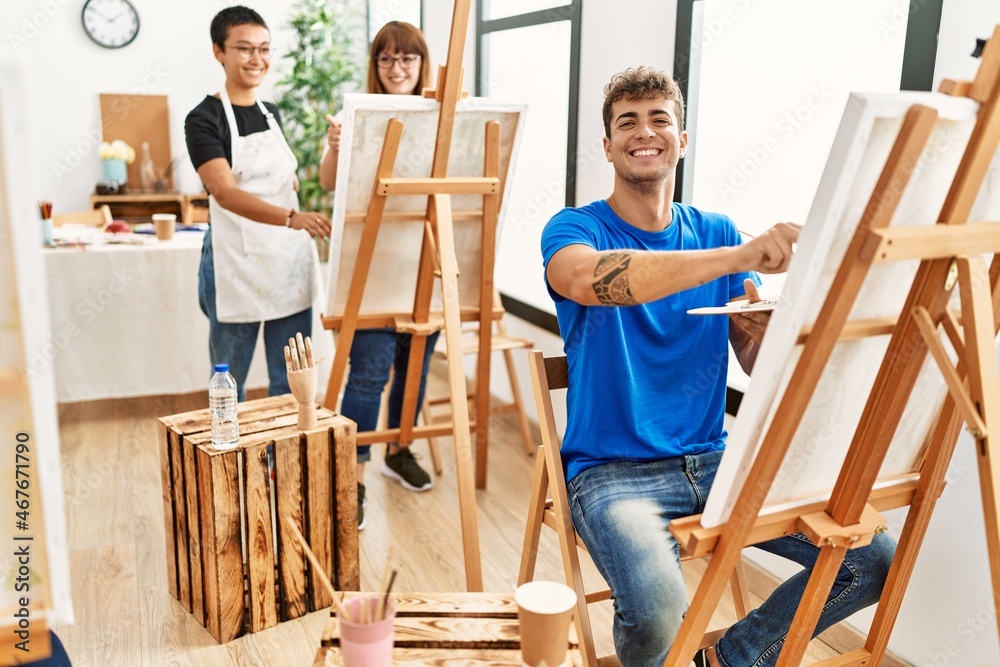 Young man smiling happy drawing with group of people at art studio.