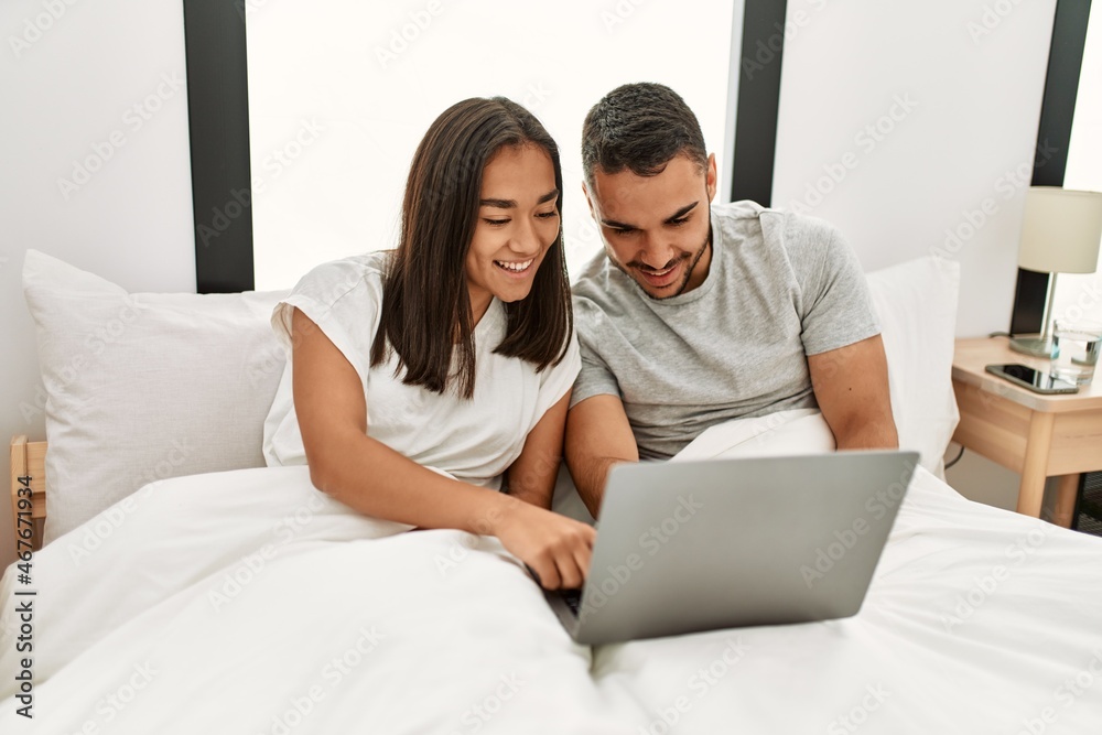 Young latin couple smiling happy using laptop at bedroom Young latin couple smiling happy using laptop at bedroom