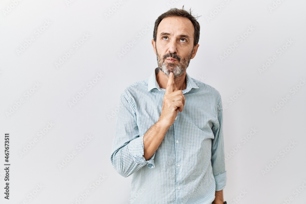 Middle age hispanic man with beard standing over isolated background thinking concentrated about doubt with finger on chin and looking up wondering Middle age hispanic man with beard standing over isolated background thinking concentrated about doubt with finger on chin and looking up wondering