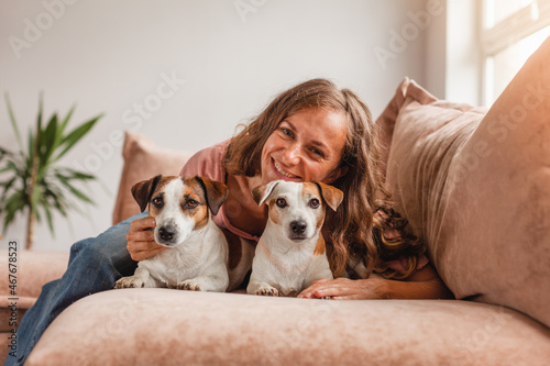 Happy girl with a dog is resting at home on the couch