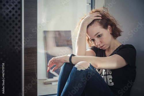 Tear-stained young girl on the windowsill
