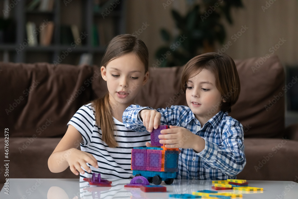 Fototapeta premium Little boy and girl playing with colorful plastic blocks, constructing truck, engaged in creative educational activity together, two kids sister and brother having fun with toys, spending weekend