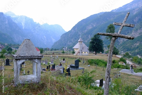 Scenery of famous mountain village Theth in Theth Valley - old cemetery next to stone church, on background the mountains of Albanian Alps 