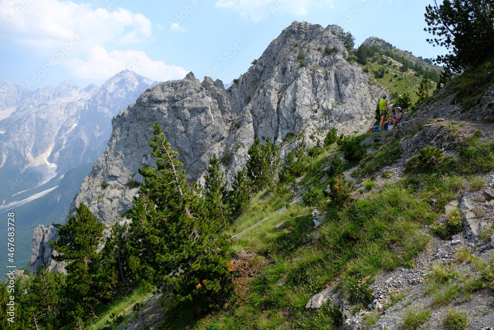 Beautiful mountain views on trail from Theth Valley to Valbona Valley in Albanian Alps. Sihouettes of tourists on path. It is one of the most beautiful high mountain trails.