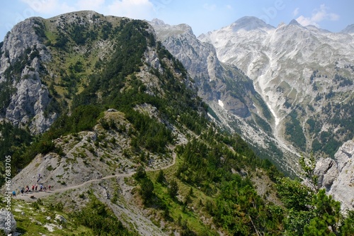 Valbona Pass (Albanian: Qafa e Valbones) on trail from Theth Valley to Valbona Valley in Albanian Alps. Sihouettes of tourists on pass. It is one of the most beautiful high mountain trails.