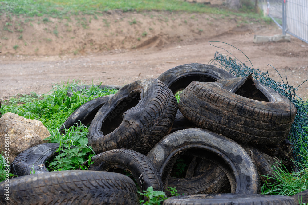 Tires in the grass, used car tires are thrown on a vacant lot, Grain effect, selective focus Tires in the grass, used car tires are thrown on a vacant lot, Grain effect, selective focus