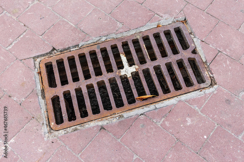 Metal rusty manhole on the street and red cobblestones