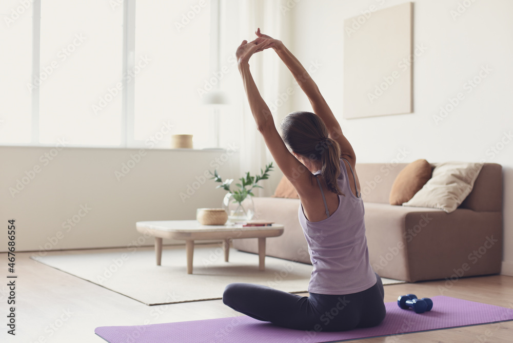 Woman doing fitness exercises at home. Girl training and practicing yoga at home. Harmony, balance, meditation, relaxation, healthy lifestyle, mindfulness concept. - obrazy, fototapety, plakaty 