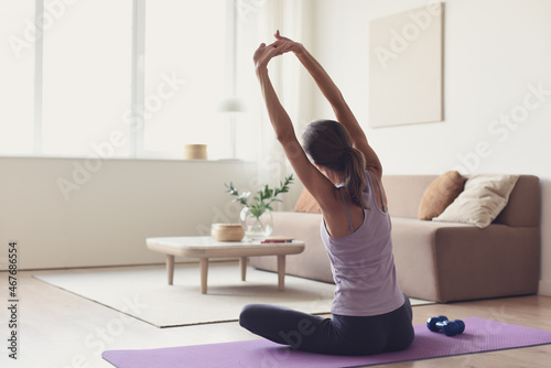 Woman doing fitness exercises at home. Girl training and practicing yoga at home. Harmony, balance, meditation, relaxation, healthy lifestyle, mindfulness concept. photo