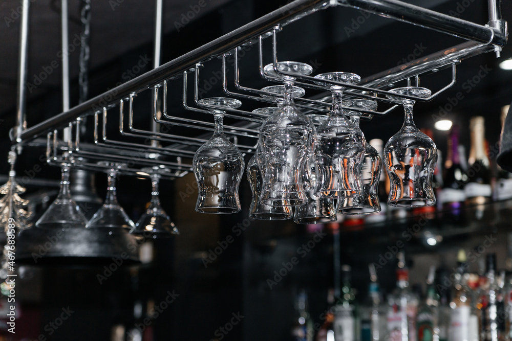 Empty and clean wine glasses hang upside down over the bar.