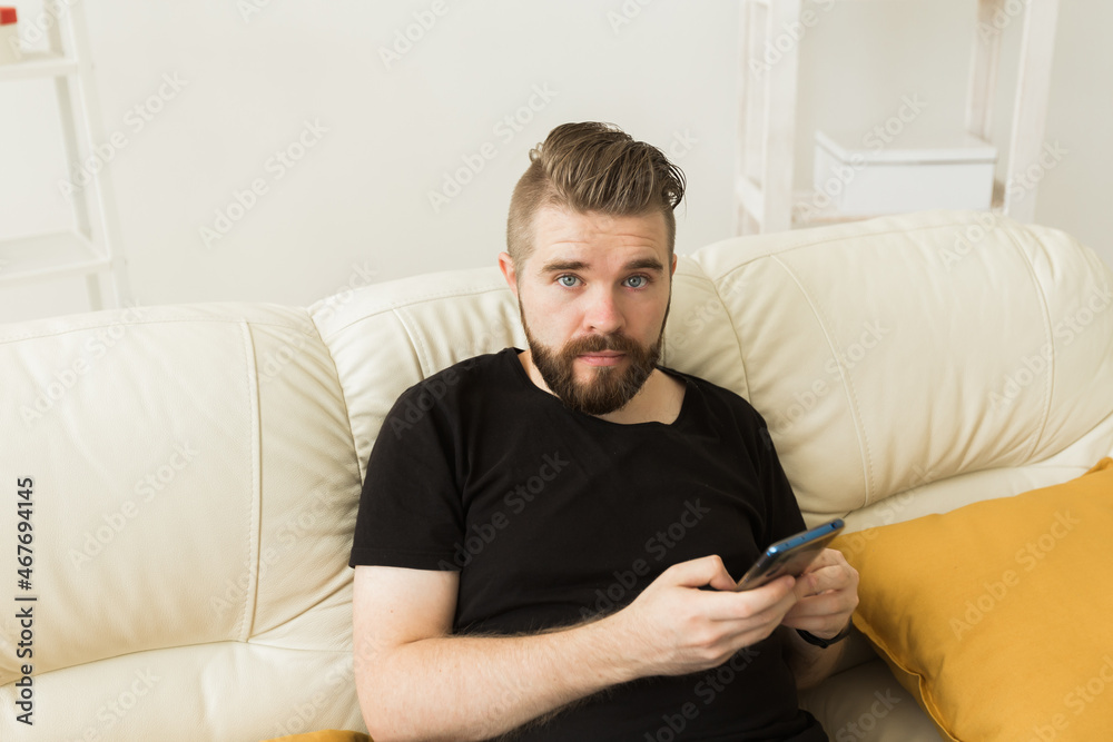 Handsome hipster man using cellphone at home. Communication leisure and technologies concept Handsome hipster man using cellphone at home. Communication leisure and technologies concept