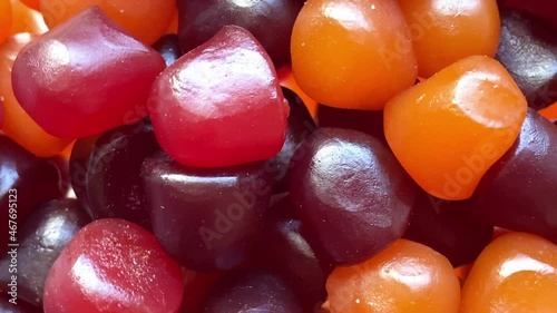 Close-up texture of red, orange and purple multivitamin gummies on white background. Healthy lifestyle concept