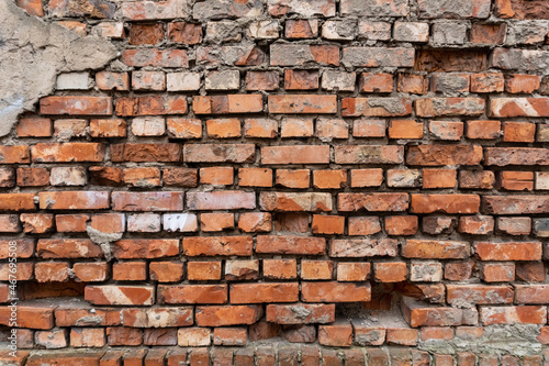 Old and damaged brick wall background with dropped out bricks.