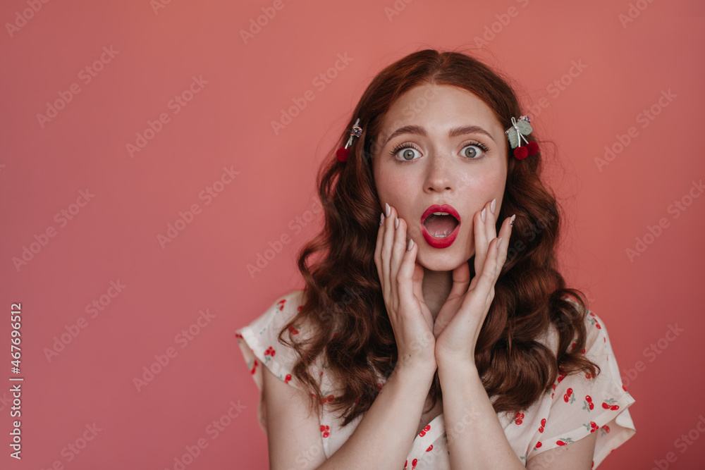Close-up portrait of shocked caucasian young girl with open mouth on isolated background. Auburn-haired female wearing white blouse depicts surprise at what she saw. Impression emotion concept. Close-up portrait of shocked caucasian young girl with open mouth on isolated background. Auburn-haired female wearing white blouse depicts surprise at what she saw. Impression emotion concept.
