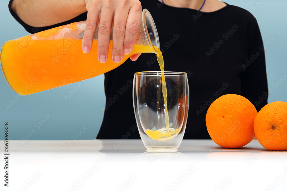 Female hand holding glass jar of fresh squeezed orange juice and pouring. selective focus Female hand holding glass jar of fresh squeezed orange juice and pouring. selective focus