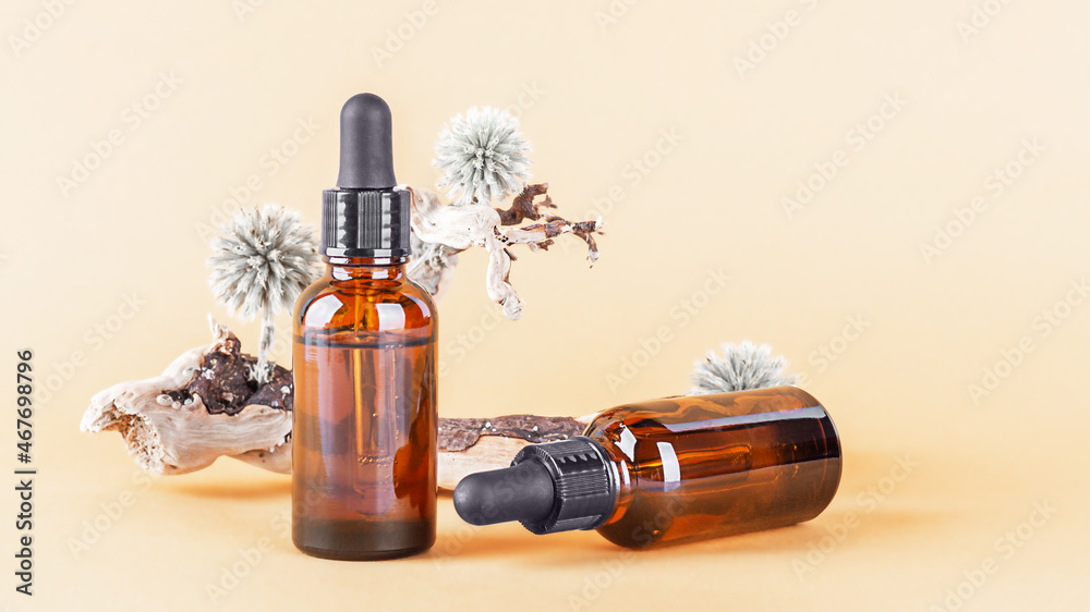 Fototapeta premium Essential oil in glass dropper bottles on a neutral beige background. Aromatherapy, massage oil, natural organic cosmetic, alternative medicine. Front view, copy space.