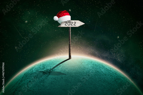 Fototapeta Naklejka Na Ścianę i Meble -  Abstract Christmas background, with a planet in the cosmic sky, and 2022 wooden signs. Abstract festive background.