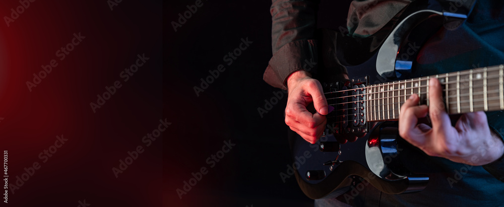 Obraz premium Male hands playing electric guitar. Musician man with black guitar at a rock concert