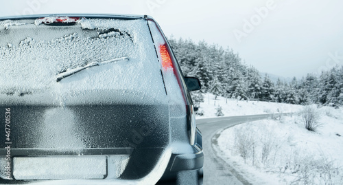 White car on a winter road through a snow covered forest. 