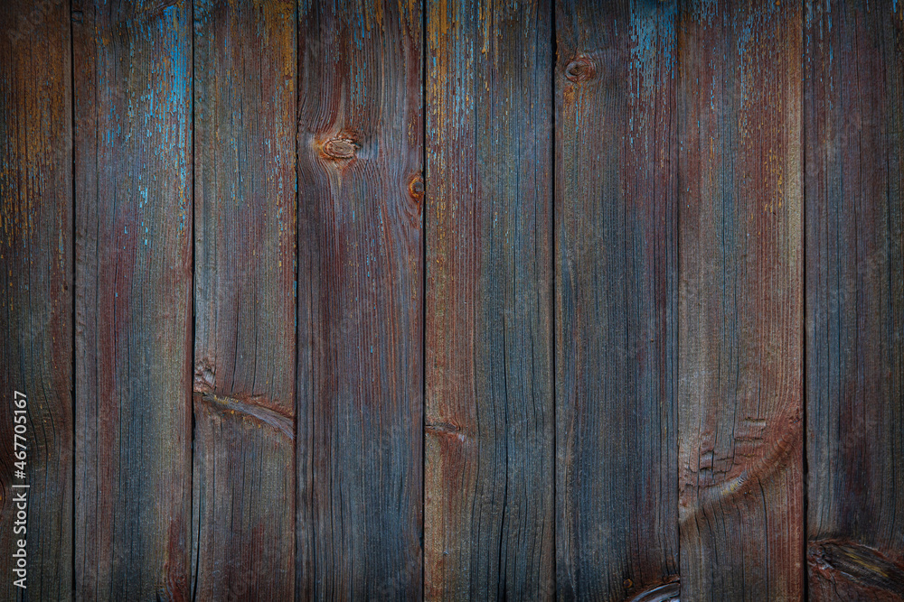 fragment of a fence made of old wooden boards with remnants of paint and nails, natural texture